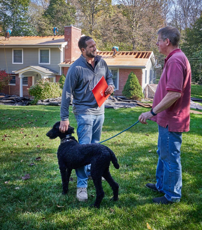 b3ed80fe-e776-4536-a230-b9d8f88032f1 A professional roofer stops to talk to a neighbor about the roof damage on his home.