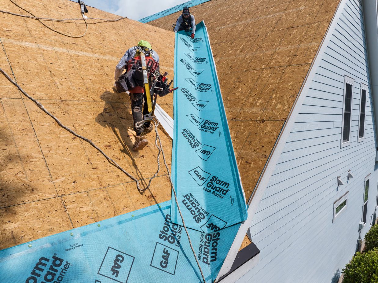Roofers install GAF StormGuard underlayment on a roof valley