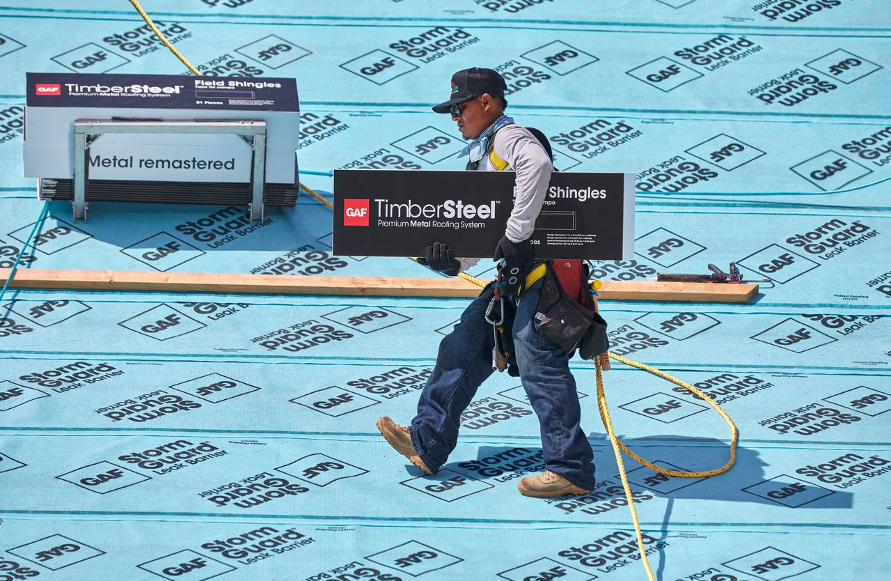 9592e661-e5fb-4b68-a5cc-f9dd619ec9d4 Roofer walks across a residential roof with StormGuard underlayment installed.