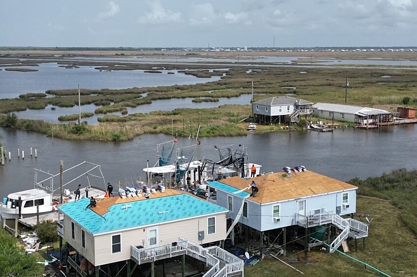 Aerial shot of roofers repairing homes in the Atakapa Ishak Chawasha community.