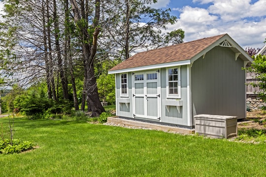 A green shed in a back yard with a garden