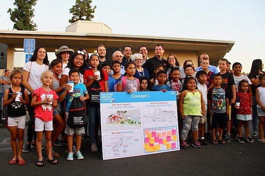 A group of Shafter community members stand before a poster with an expansion concept and feedback.