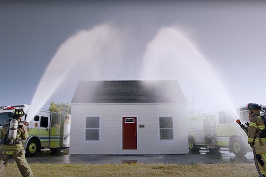 fireman spraying a hose on a gaf shingle roof