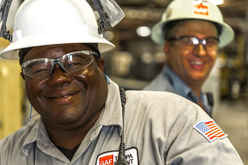 Smiling employees wearing hard hats in a manufacturing plant