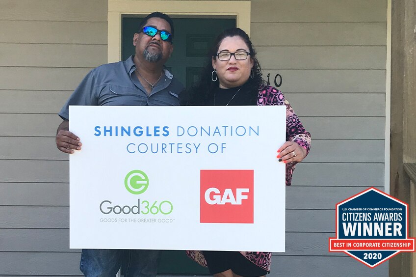 Homeowners standing on their front porch holding a sign
