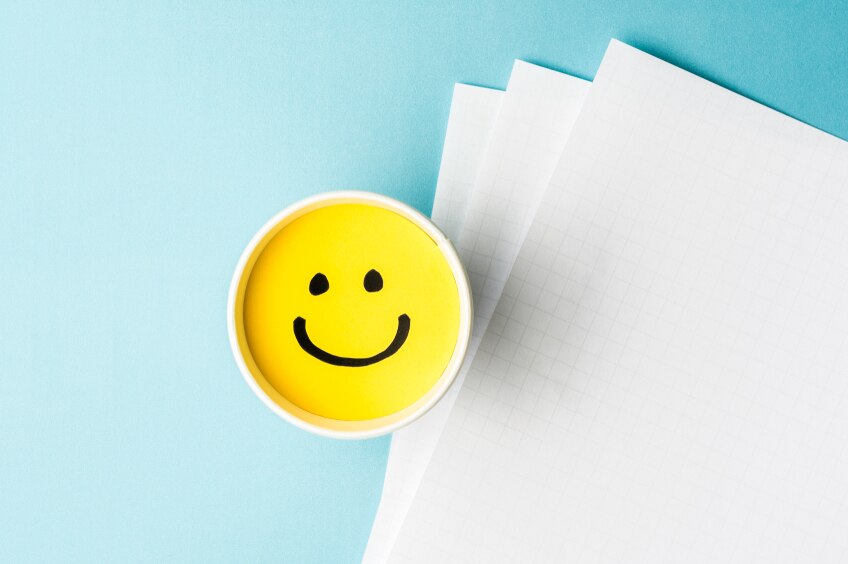 Yellow happy face in cup with papers