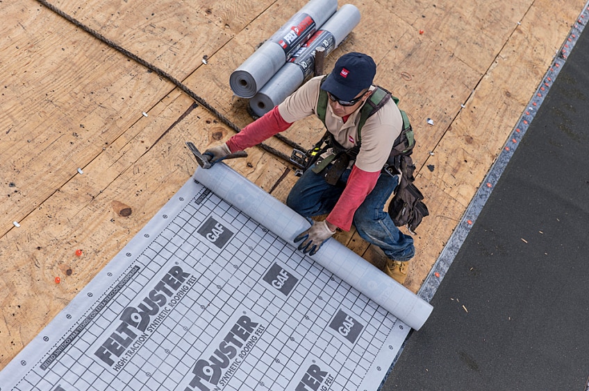 Contractors installing roof underlayment