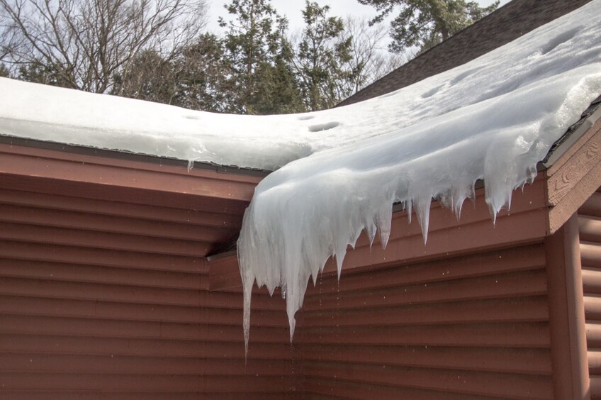 Heavy buildup of ice along the edge of a residential roofline.