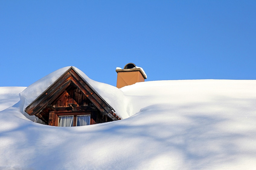 Thick snow covers the gables of a house