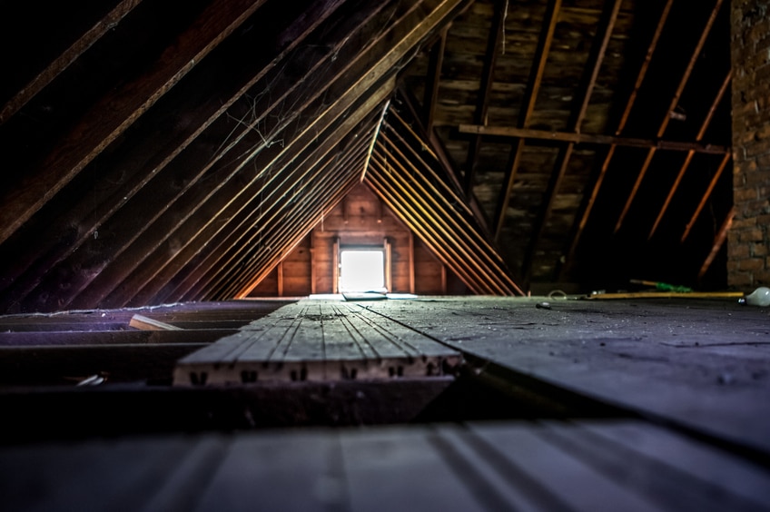 Light shines through a small square window in an empty attic
