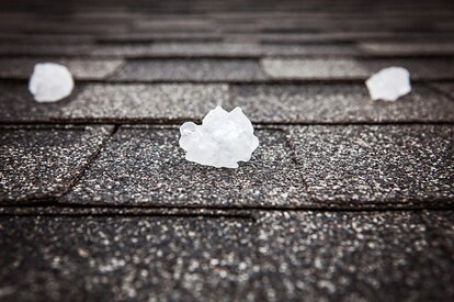 An asphalt shingle roof with hail balls laying on it.