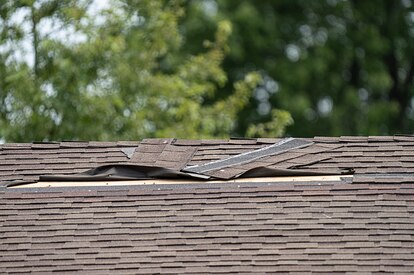 Roof shingles that have been damaged by high winds in a storm