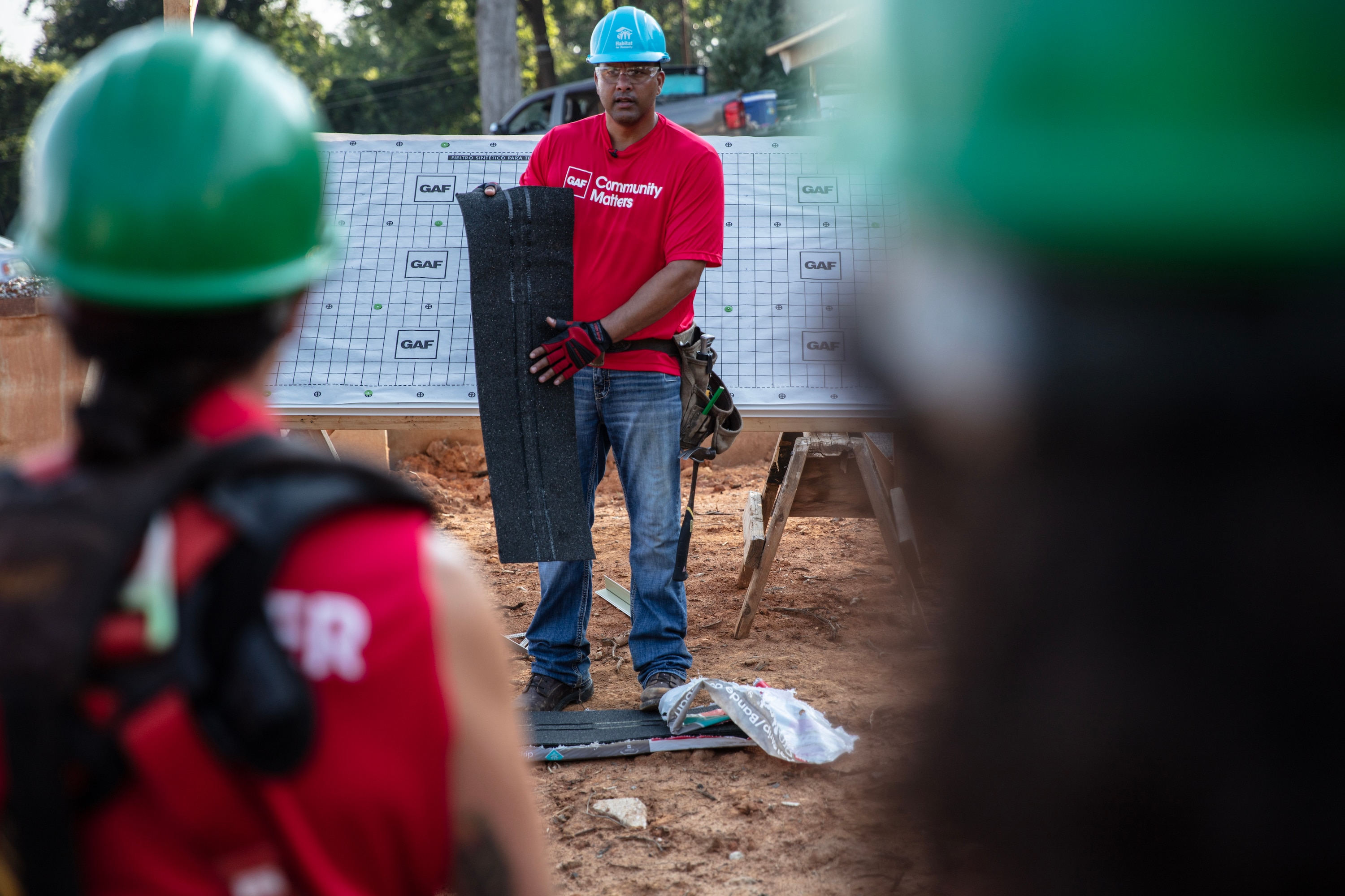 Gary Pierson holds a roofing shingle as he educates volunteers