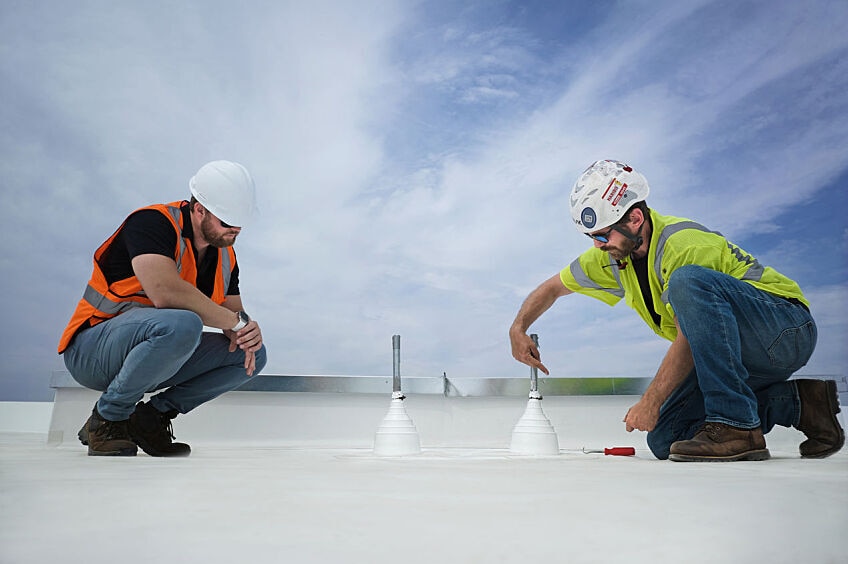 Two roofing contractors on a commercial roof at work