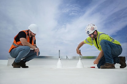 Two roofing contractors on a commercial roof at work