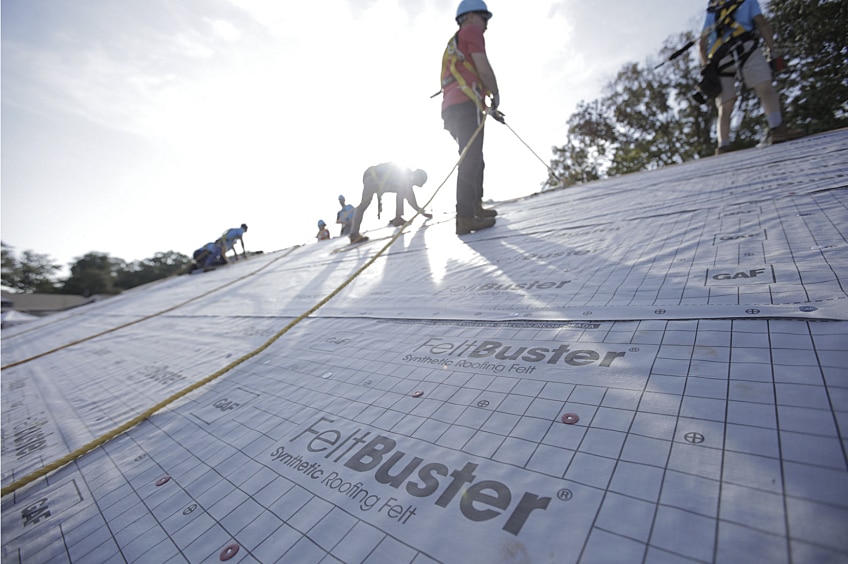 Contractor on a roof install with workers