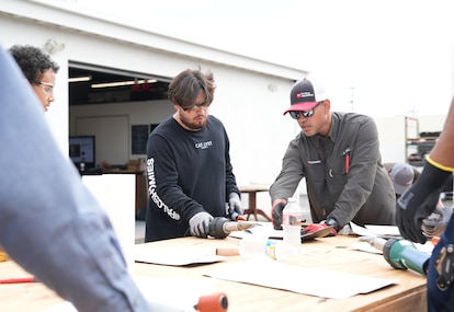 A GAF Roofing Academy instructor shows a student how to cut and measure roofing materials.