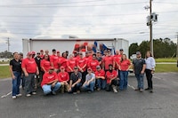 Volunteers from GAF plant communities fill cardboard boxes with food.