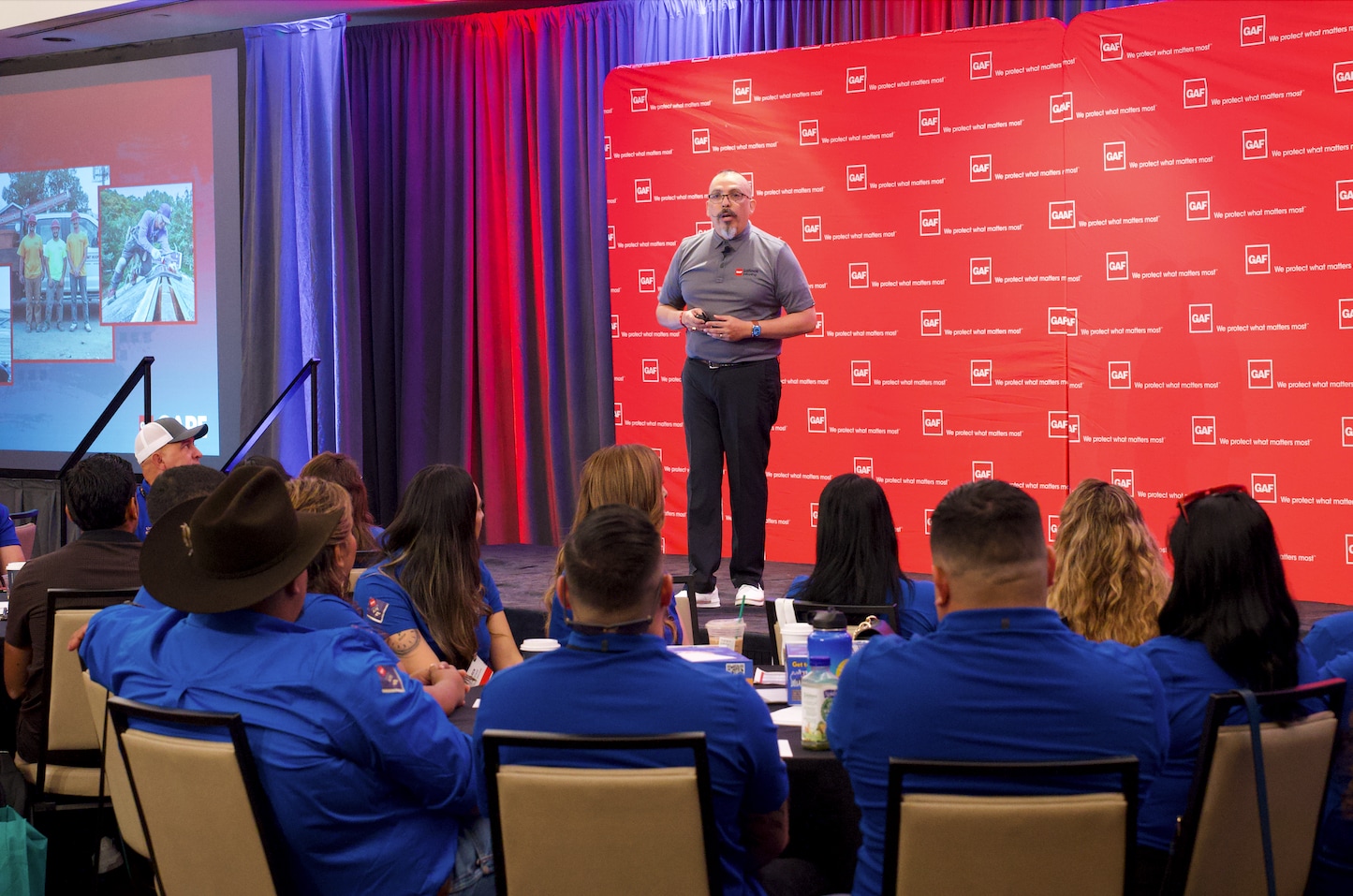 An audience of latino roofing professionals listens to Alan Lopez on the stage at the LIR conference