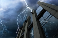 Lightning strikes a tall commercial building during a nighttime storm.