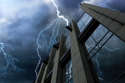 Lightning strikes a tall commercial building during a nighttime storm.