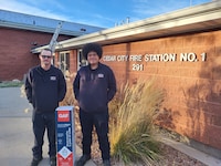 Two firefighters pose with GAF roofing materials.