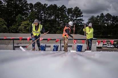 Roofers installing GAF Roof Coatings on a commercial roof