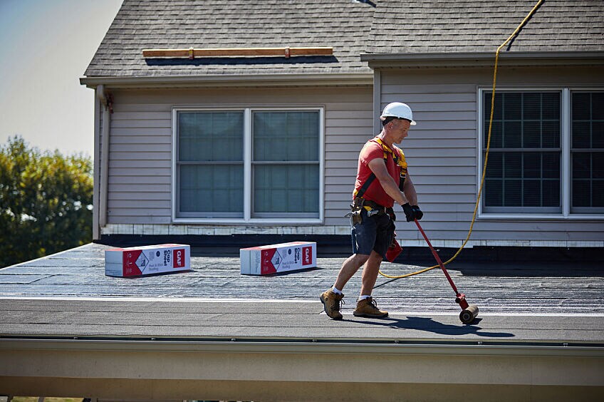 A roofer installs GAF LIBERTY™ Self-Adhering Base/Ply Sheet