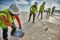 A group of five roofers installing GAF PVC products on a commercial roof