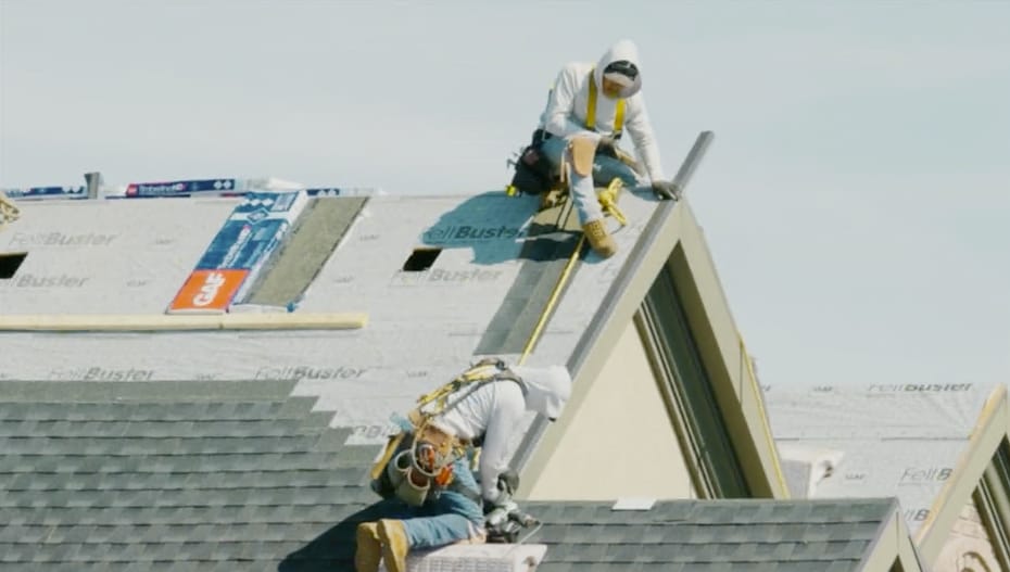 Two roofing technicians in safety harnesses installing GAF Timberline HDZ® shingles and FeltBuster underlayment on a residential roof in Utah
