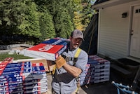 A roofer carries a bundle of GAF Timberline HDZ shingles.