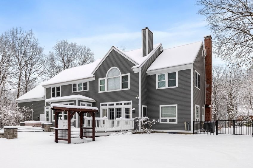 This snowy house with a large tree in the foreground is a striking image for a winter photo album