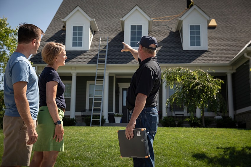 Contractor pointing to a house speaking to homeowner