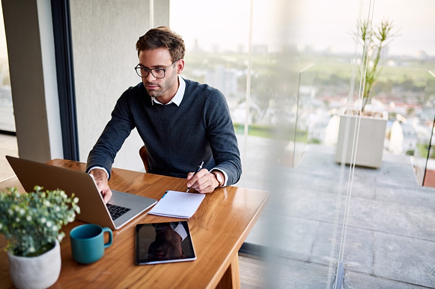 Business leader with laptop writing business plan