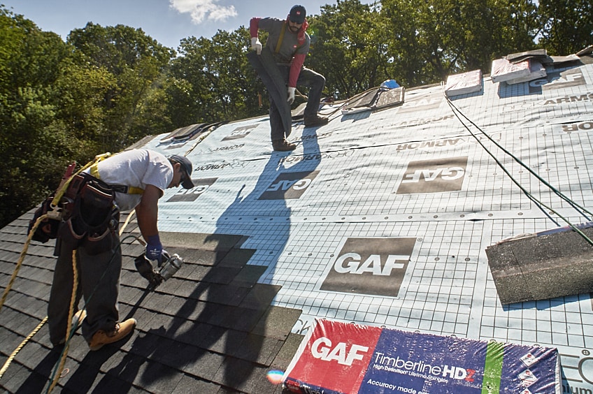 A contractor with a helmet working on an angled roof