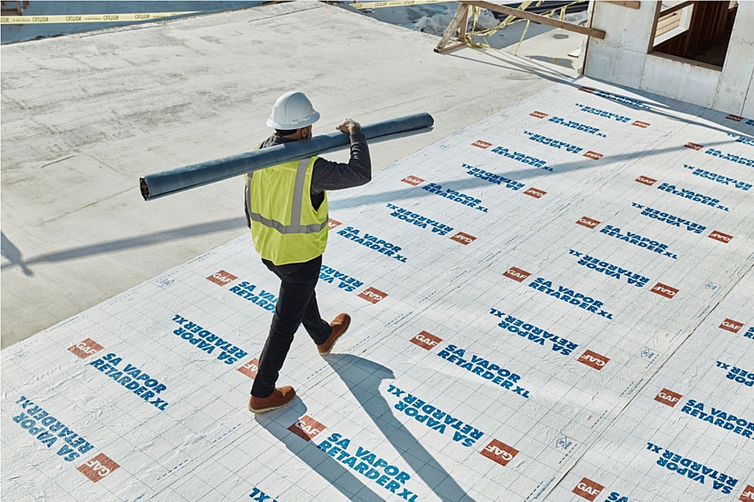 A GAF certified commercial roofer walking on a flat roof.