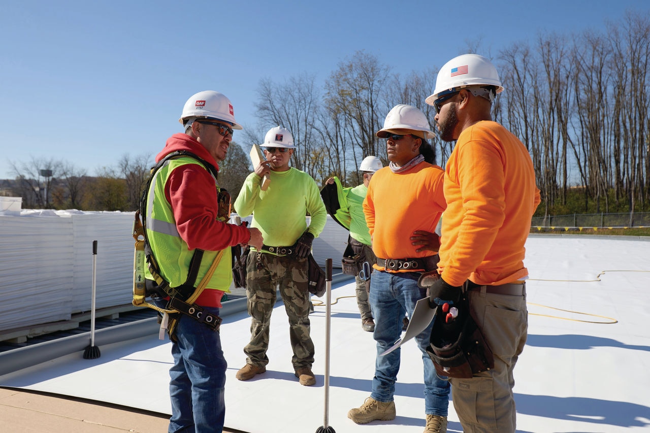 A commercial roofing contractor working with his team to install GAF products on a flat roof.