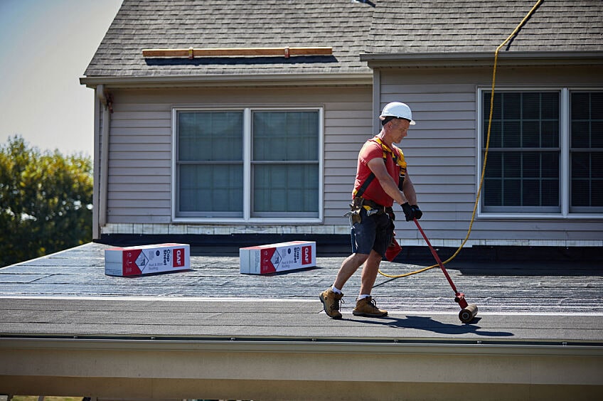 A roofer installs GAF LIBERTY™ Self-Adhering Base/Ply Sheet