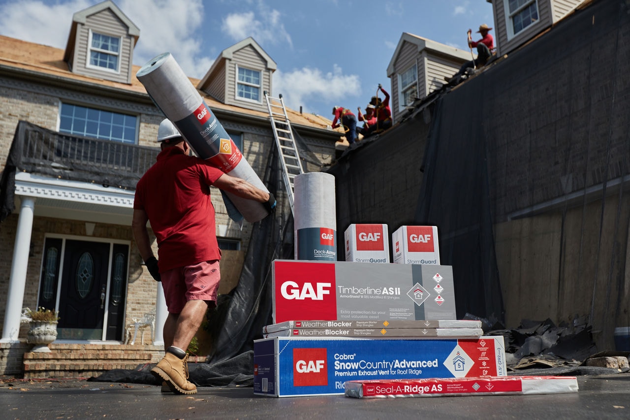 A contractor carrying GAF materials up to a roof