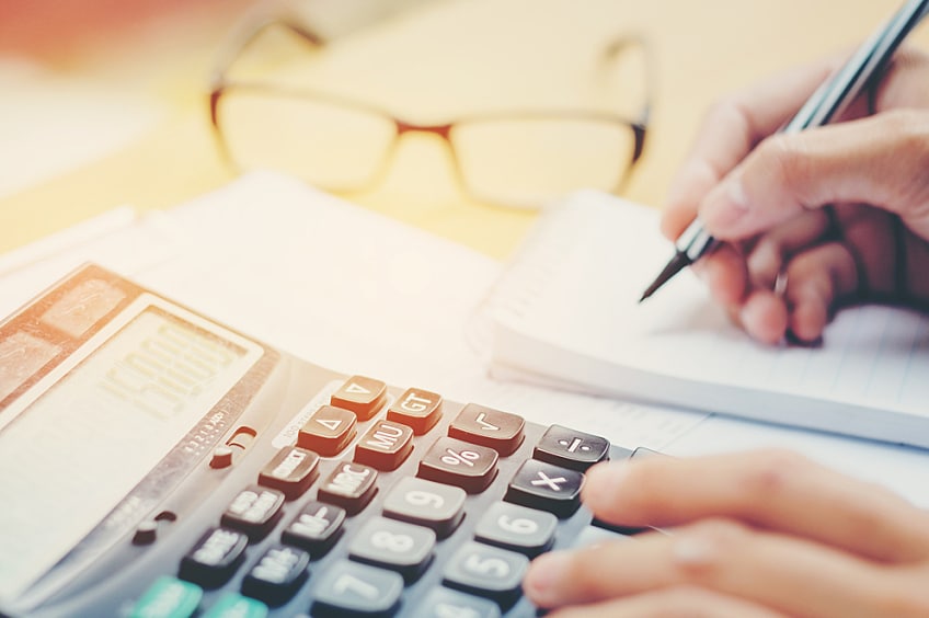 A woman in business clothing sits at a desk looking at tax forms