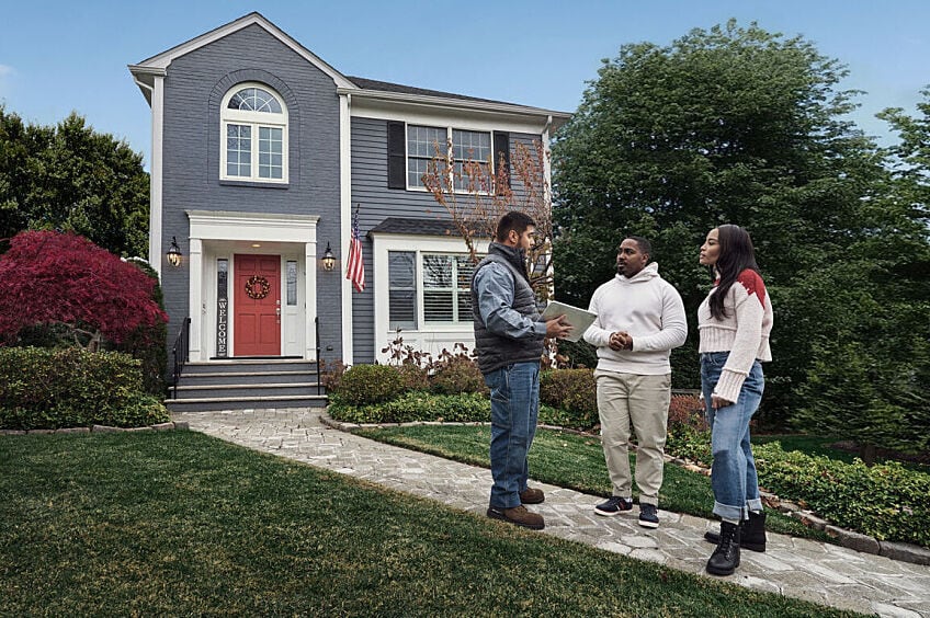A contractor inspects a house's roof.