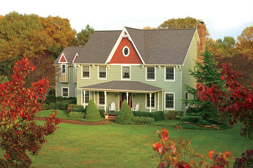 A home with Timberline Cool Series shingles surrounded by trees and green grass