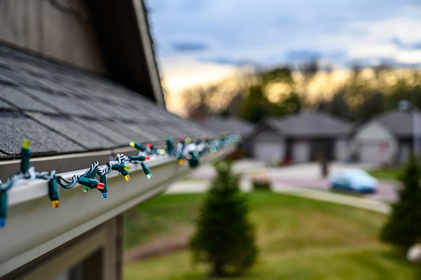 Holiday lights lining a modern home with roof shingles